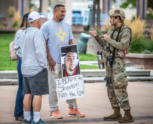 Luiz Otero, centre, holds a sign with his son Elias Otero's image, who was shot and killed a couple years ago in Albuquerque, N.M., as people attend a Second Amendment Protest in response to Gov. Michelle Lujan Grisham's recent public health order suspending the conceal and open carry of guns in and around Albuquerque for 30-days, Tuesday, Sept. 12, 2023, in Albuquerque, N.M. (AP Photo/Roberto E. Rosales)