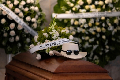 The hat and sunglasses of Dominican singer Rubby Perez, who died in the roof collapse at the Jet Set nightclub during his merengue concert, sit on his casket during his wake at the Eduardo Brito National Theater in Santo Domingo, Dominican Republic, Thursday, April 10, 2025. (AP Photo/Matias Delacroix)