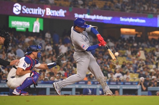 Chicago Cubs' Miguel Amaya, right, hits a two-run home run as Los Angeles Dodgers catcher Austin Barnes kneels at the plate during the eighth inning of a baseball game, Saturday, April 12, 2025, in Los Angeles. (AP Photo/Mark J. Terrill)