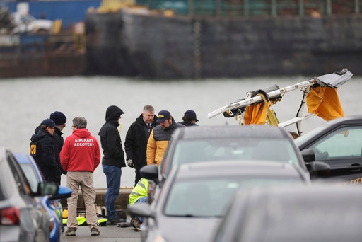 Investigators with the National Transportation Safety Board investigate the wreckage of a site seeing helicopter, Friday, April 11, 2025, that crashed into the Hudson River a day earlier in Jersey City, N.J. (AP Photo/Adam Hunger)
