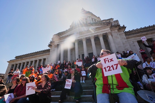 People gather on the steps of the Washington State Capitol Building during a rally advocating for lawmakers to change and pass House Bill 1217, a rent-control bill, Friday, April 18, 2025, in Olympia, Wash. (AP Photo/Lindsey Wasson)